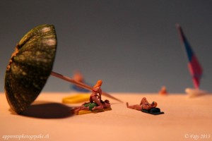 Scène de vacances réalisé avec un parasol courgette et de petits personnages sur la plage au bord de l'eau