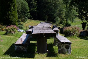 Bancs et tables massifs et rustiques devant l'entrée du Gîte