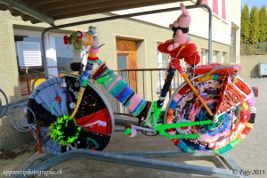 Un vélo entièrement décoré de laine sous le préau d'une école